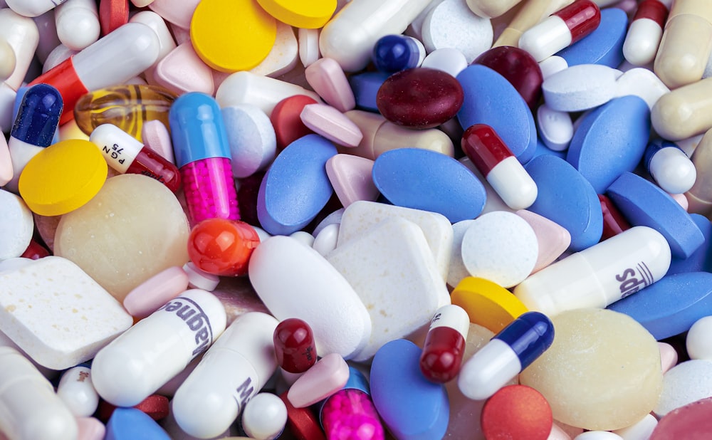 Capsule medication spilling from a bottle next to a glass on a table